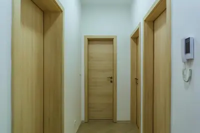 a hallway with wooden doors and a phone on a wall at Opium Mar Apartments in Petrovac na Moru