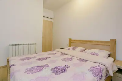 a bedroom with a bed with a purple blanket and pillows at Opium Mar Apartments in Petrovac na Moru