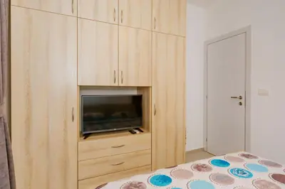 a bedroom with a tv in a wooden cabinet at Opium Mar Apartments in Petrovac na Moru
