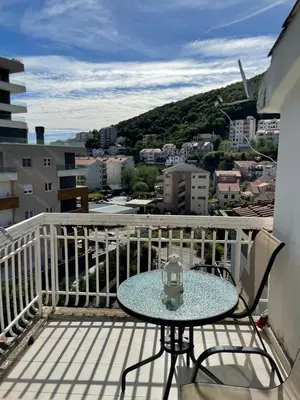 a table on a balcony with a view of a city at Nikola's apartment in Budva
