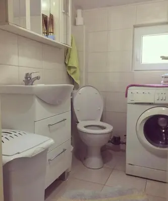 a bathroom with a toilet and a sink and a washing machine at Nikola's apartment in Budva
