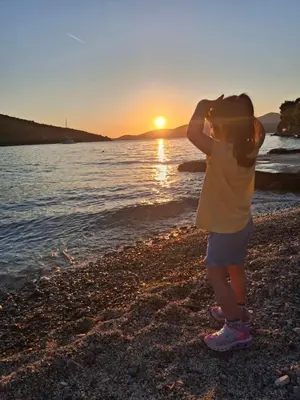 a young child standing on the beach watching the sunset at Apartman sa sopstvenim dvoristem , pored mora in Bigovo