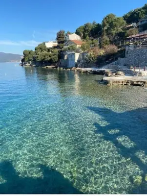 a body of water with a group of people in the water at Apartman sa sopstvenim dvoristem , pored mora in Bigovo