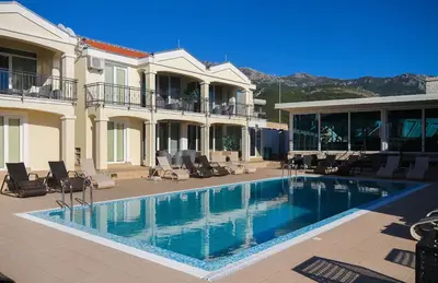 a large swimming pool in front of a house at Apart Hotel Spa Resort Becici, Budva Апартаменты с двумя мастер-спальнями in Becici
