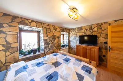 a bedroom with a bed and a stone wall at Village Villa Dobrski Dvori in Cetinje