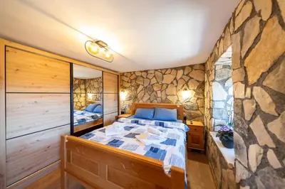 a bedroom with a bed and a stone wall at Village Villa Dobrski Dvori in Cetinje