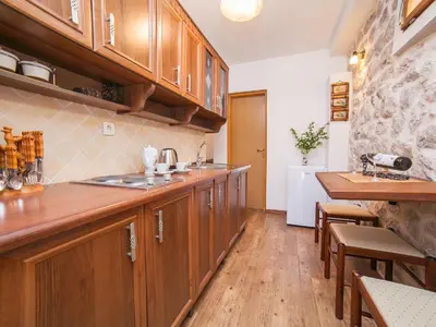 a kitchen with wooden cabinets and a wooden floor at Apartments Ana in Kotor