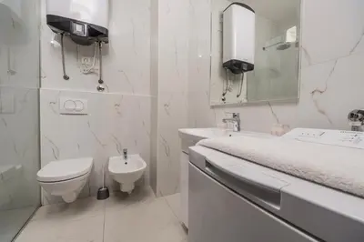 a white bathroom with a toilet and a sink at Deluxe Apartments Shine in Becici