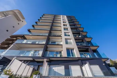 a tall apartment building with a blue sky in the background at Deluxe Apartments Shine in Becici