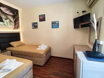 a small room with two beds and a tv at Palma Rooms & Suites Budva in Budva