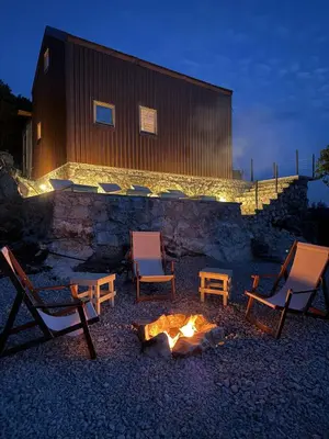 a group of chairs around a fire in front of a building at Above the Lake in Rogani