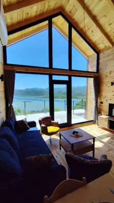 a living room with a blue couch and a large window at Above the Lake in Rogani