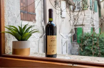 a bottle of wine and two wine glasses on a window at lifekotor in Kotor