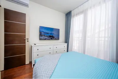 a bedroom with a bed and a dresser and a window at Sea View Budva in Budva