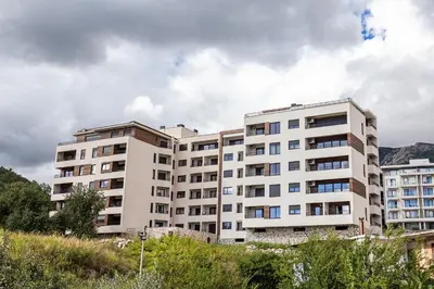 a white apartment building with mountains in the background at Apartment LEMON in Becici