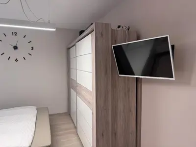 a room with a tv on a wall with a clock at Apartman Ari in Sveti Stefan