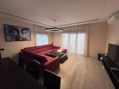 a living room with a red couch and a television at Apartman Ari in Sveti Stefan