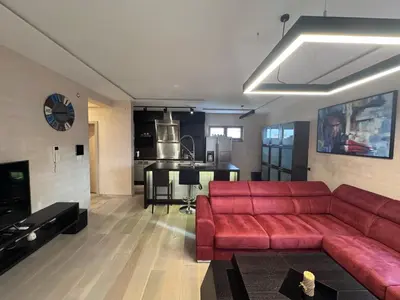 a living room with a red couch and a kitchen at Apartman Ari in Sveti Stefan