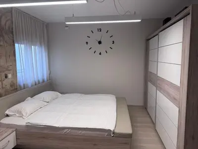 a bedroom with a bed and a clock on the wall at Apartman Ari in Sveti Stefan