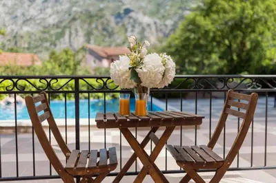 a table with two chairs and a vase with flowers at Pool Home near the Old Town in Kotor