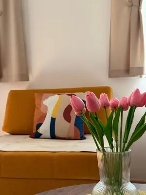 a vase of pink tulips on a table with a bed at Shi Apartment Bar in Bar
