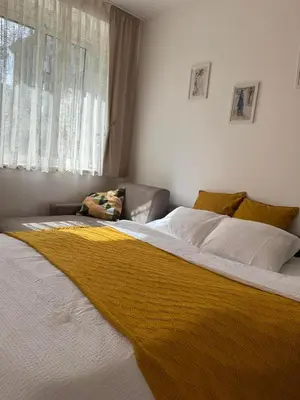 a bedroom with a large bed with a yellow blanket at Shi Apartment Bar in Bar
