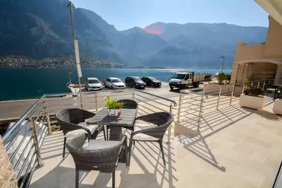 a table and chairs on a balcony with a view of the water at Apartments Jovanovic in Kotor