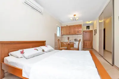 a bedroom with a large white bed and a kitchen at Apartments Jovanovic in Kotor