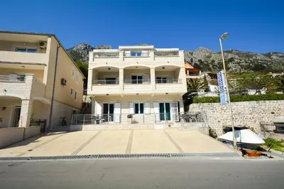 a large white building with mountains in the background at Apartments Jovanovic in Kotor