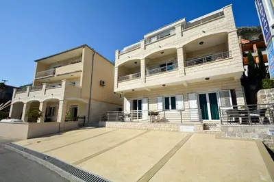 a large white building with a large parking lot at Apartments Jovanovic in Kotor