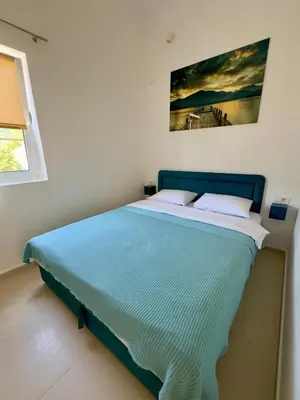a bedroom with a blue bed with a painting on the wall at Spacious two bedroom apartment with free parking in Dobrota