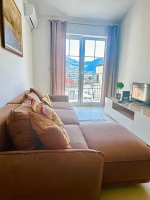 a bedroom with a couch and a large window at Spacious two bedroom apartment with free parking in Dobrota