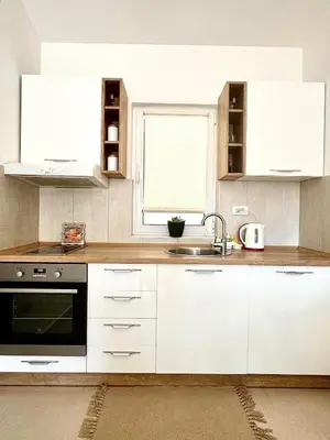 a kitchen with white cabinets and a sink and a window at Spacious two bedroom apartment with free parking in Dobrota