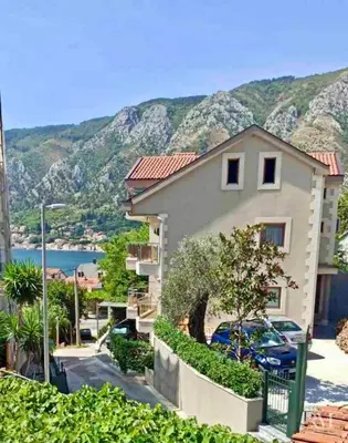 a house with a view of the water and mountains at Spacious two bedroom apartment with free parking in Dobrota