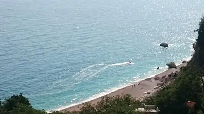 a beach with people swimming in the water at PerDo in Perazića Do