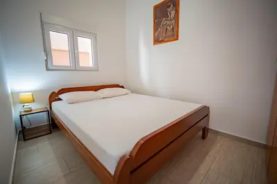 a bedroom with a bed in a room with a window at Apartmani Bonaca in Tivat