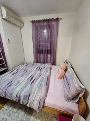 a bedroom with a bed with a purple curtain at Mimoza Apartment in Budva in Budva