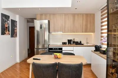 a kitchen with a table with chairs and a refrigerator at Moderan dvosoban stan in Budva