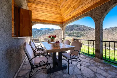 a dining room with a table and chairs on a balcony at Handmade house Rijeka Crnojevica in Donje Selo