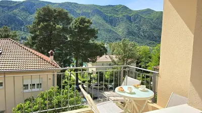 a balcony with a table and chairs and mountains at Luxury Suite in Kotor