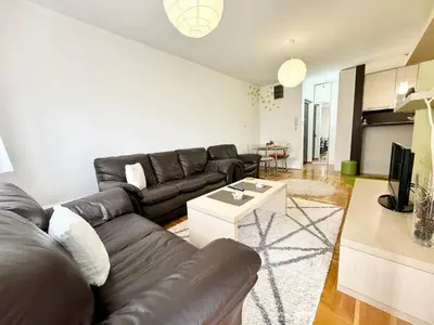 a living room with a leather couch and a table at Şehir merkezi manzaralı modern in Podgorica