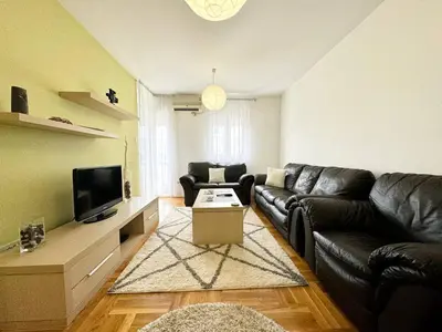 a living room with a black leather couch and a tv at Şehir merkezi manzaralı modern in Podgorica
