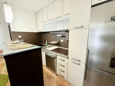 a kitchen with white cabinets and a stainless steel refrigerator at Şehir merkezi manzaralı modern in Podgorica