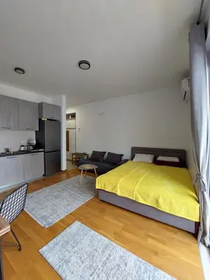 a bedroom with a yellow bed and a kitchen at TiN Apartment in Ulcinj