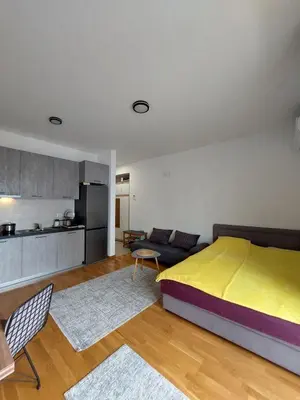 a bedroom with a large bed and a kitchen at TiN Apartment in Ulcinj