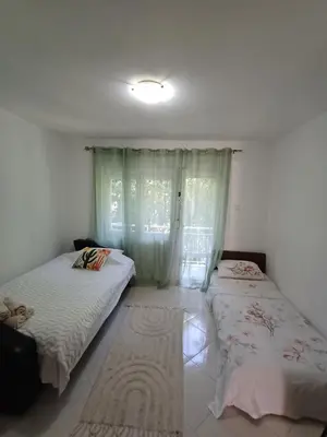 two beds in a room with a window at Pampas Family Apartment in Dobrota