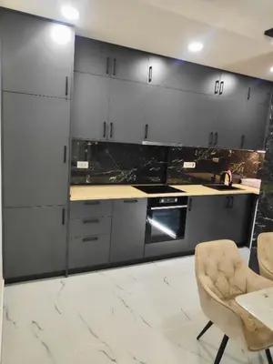 a kitchen with gray cabinets and a table and a chair at Apartmani Đurović in Becici