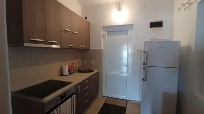 a kitchen with a white refrigerator and wooden cabinets at Cozy 2-Bedroom Apartment in Bigovo