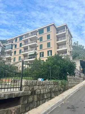 a large apartment building with a stone wall in front of a building at Katarina17 in Becici