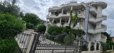 a white building with a fence in front of it at OliveGarten Apartments in Ulcinj